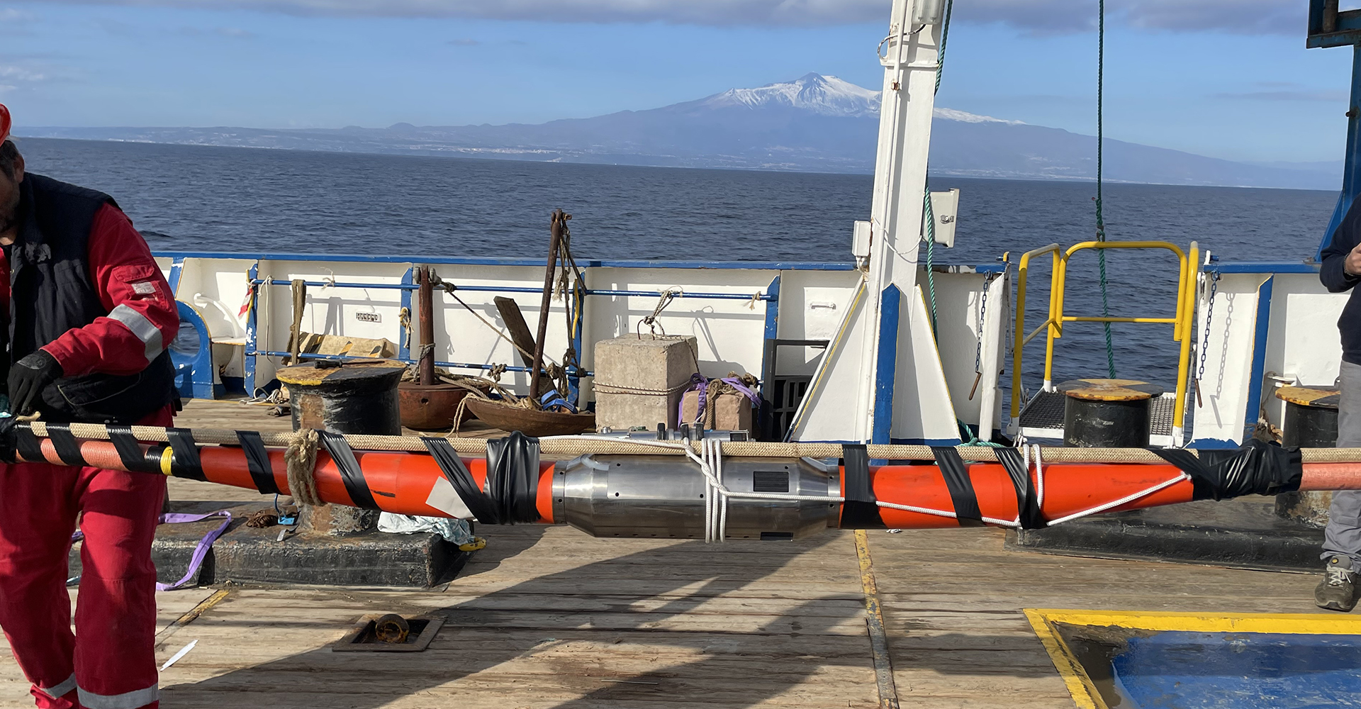 Instrument pod being deployed from a ship with Mount Etna in background